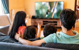 Parents and their two children watching TV together at home